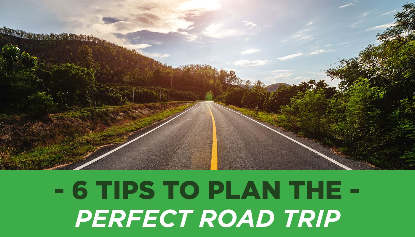 6 Tips to Plan the Perfect Road Trip - An image of a highway with a scenic background of trees and a blue, cloudy sky.
