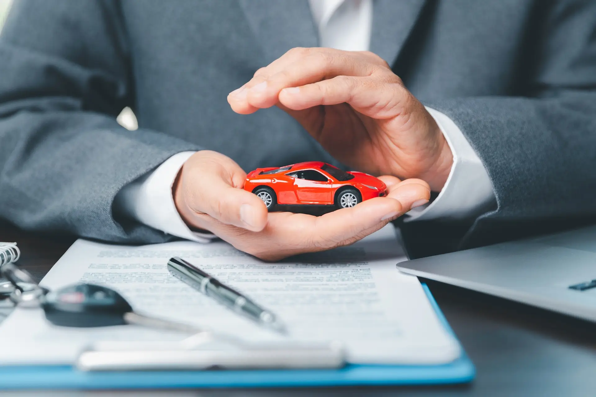 what to look for when shopping for car insurance quotes - An image of a car insurance agent holding a toy car, representing a protected / insured vehicle.