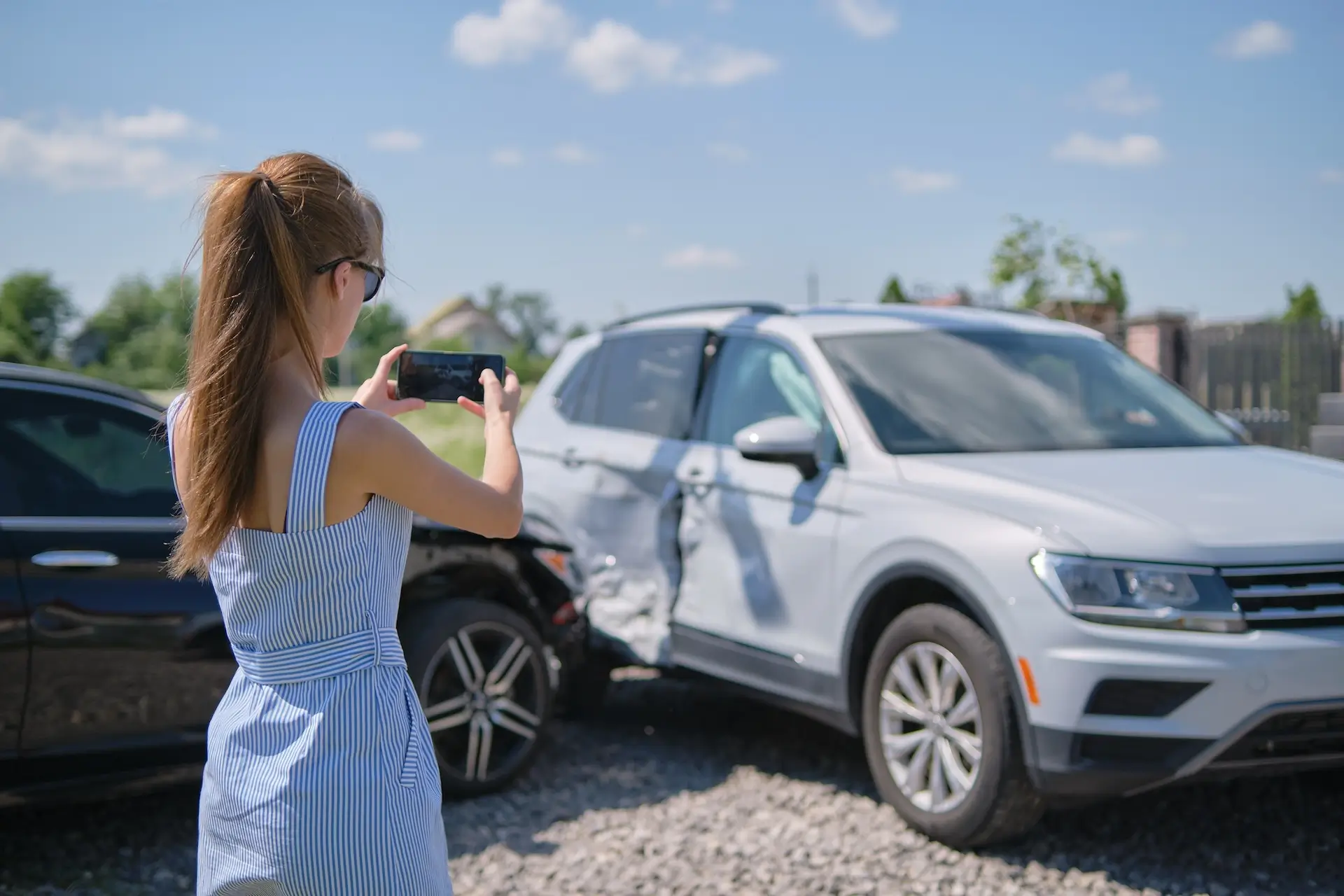 when is a car considered totaled? - An image of a woman taking a picture of a damaged car from a car accident.