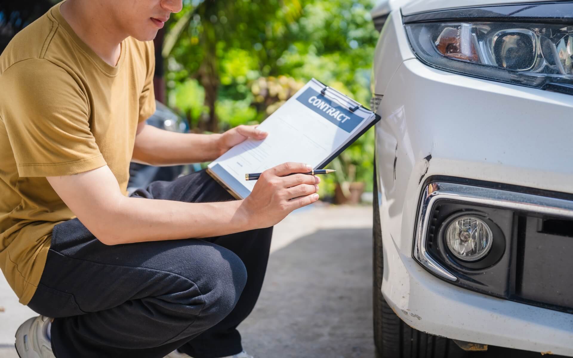 A car insurance adjustor assessing a vehicle's post-accident damage. This image is for the blog, "what questions do car insurance companies ask after an accident".