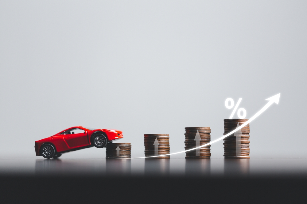 how are car insurance rates calculated - An image of a toy car "Driving up" a stack of coins.