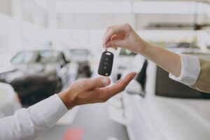 Is Insurance Cheaper on a New Car - An image of a car insurance person handing the keys to a new car buyer