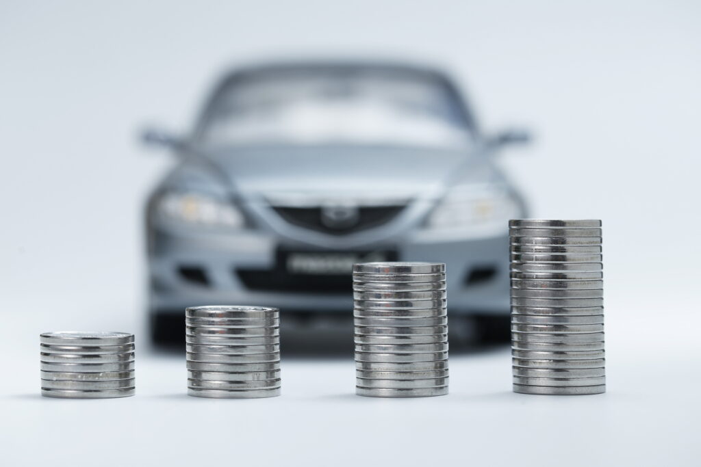 Stacks of coins beside a miniature car representing budget-friendly auto insurance savings