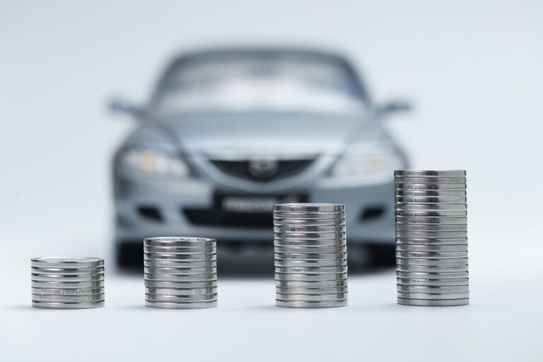 Stacks of coins beside a miniature car representing budget-friendly auto insurance savings