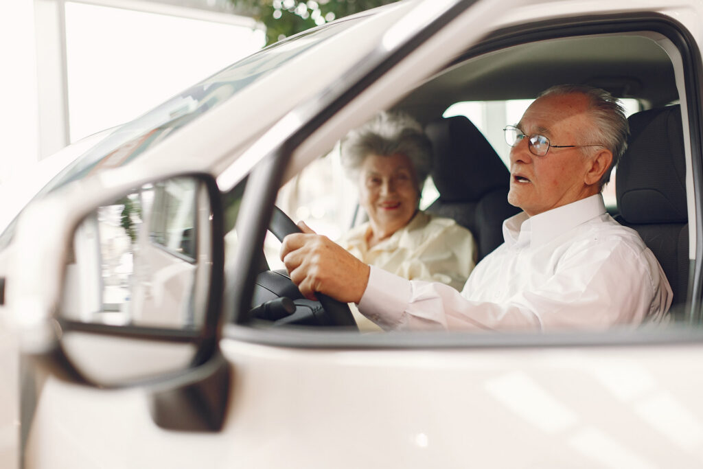 Senior couple discussing automobile coverage and safety features in a car dealership