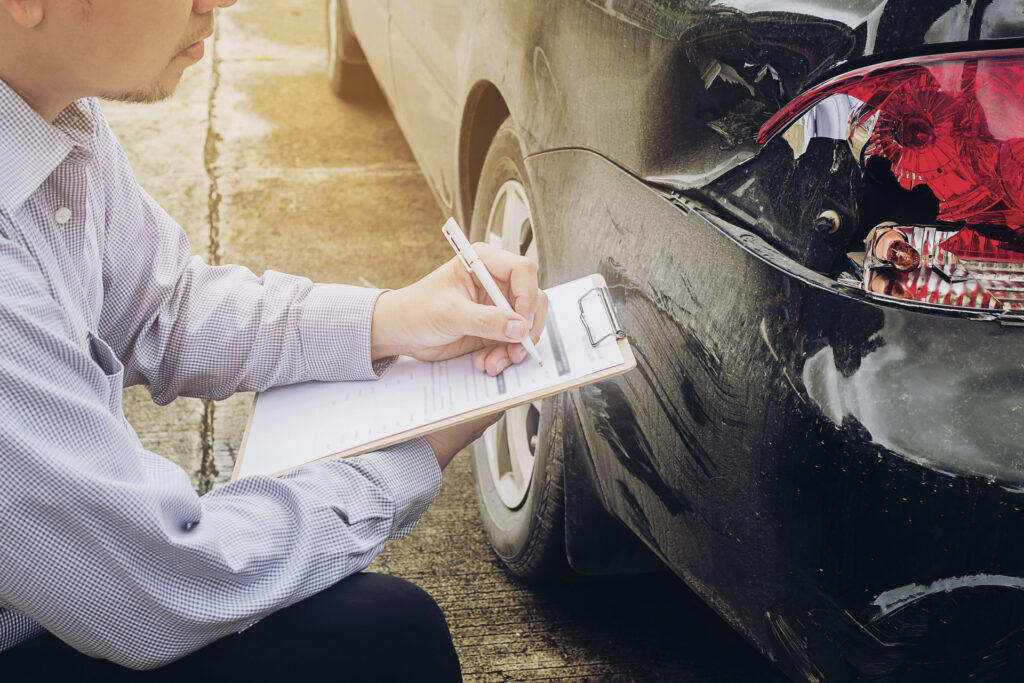 Insurance adjuster examining vehicle damage and documentation for an auto accident claim