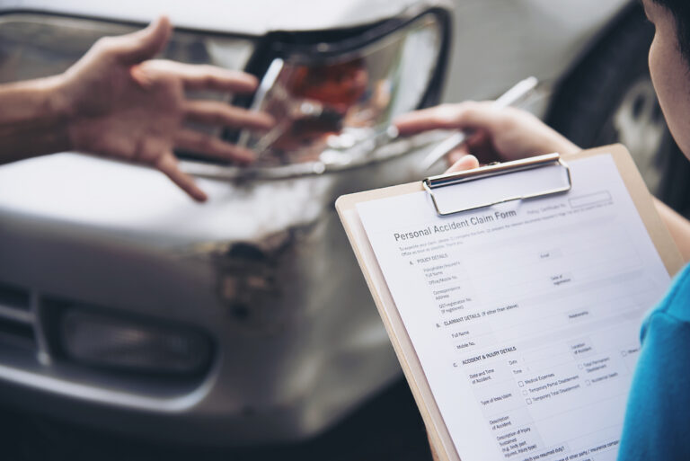 Insurance agent reviewing a car accident claim at the scene