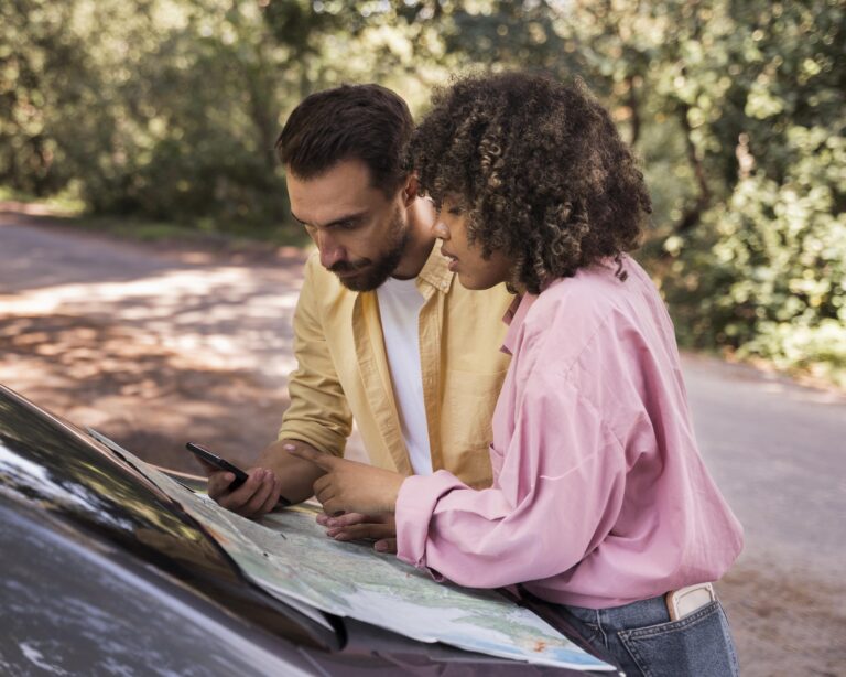 Couple outdoors reviewing a road map beside their vehicle during travel