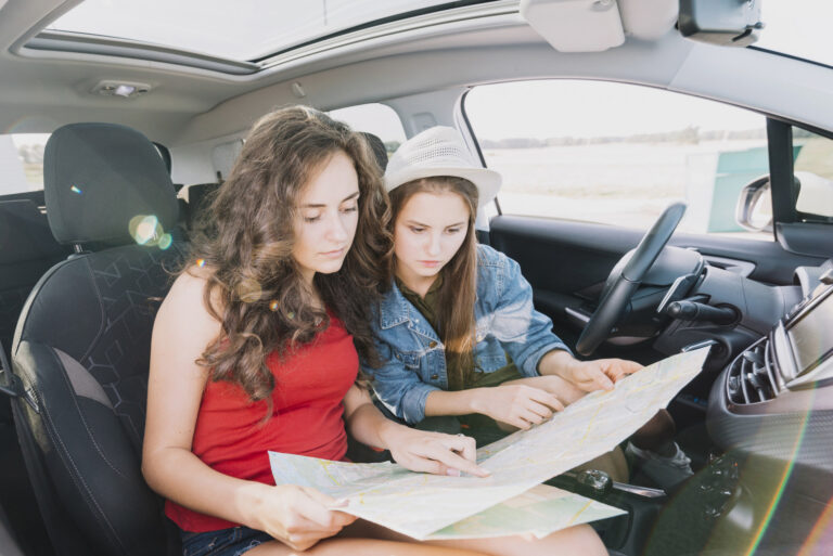 Two women consulting a road map for highway navigation and driving directions